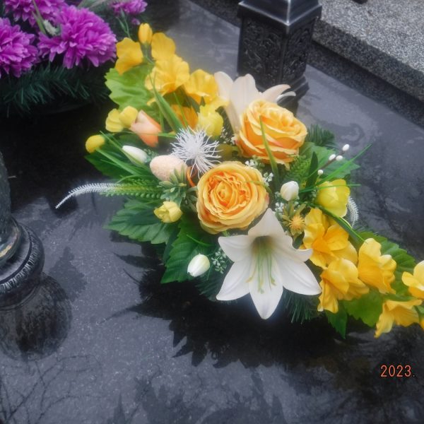 Nowa wiązanka sztucznych kwiatów na grobie